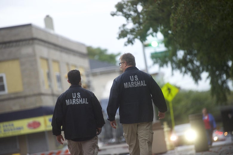 U.S. Marshals monitor activity outside a courthouse.